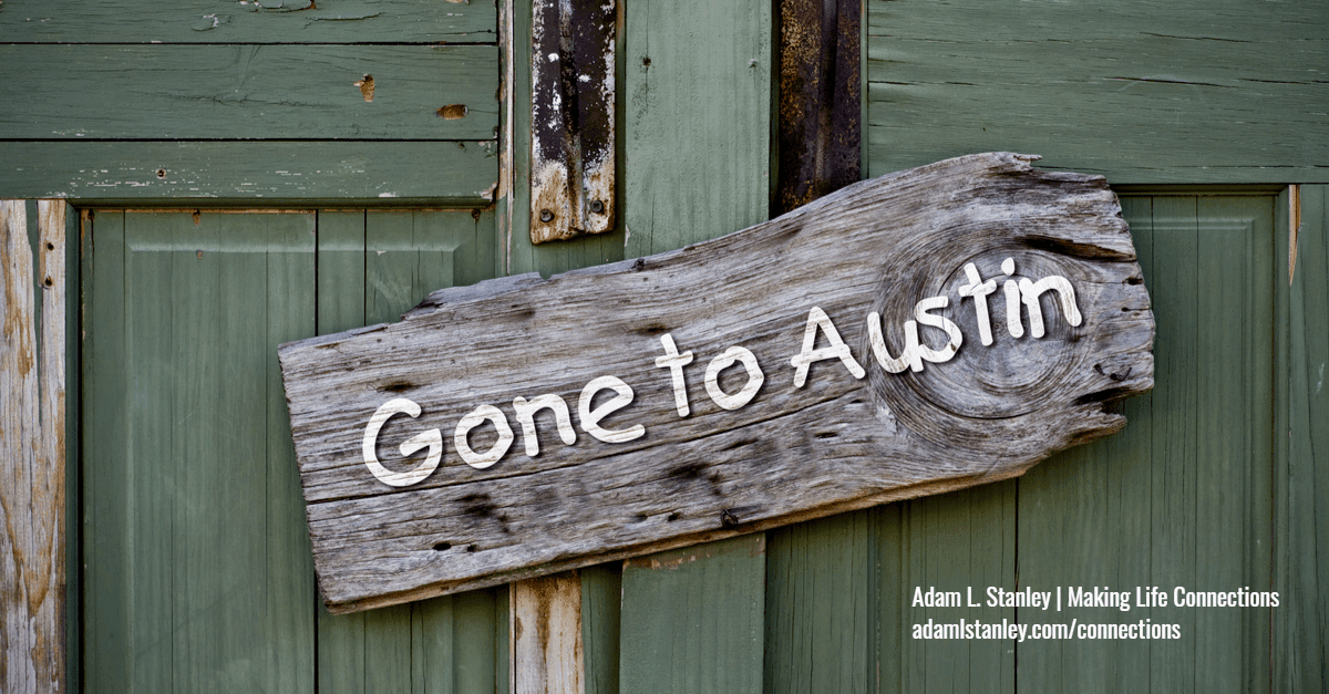 gray wooden sign on a green door that says Gone to Austin